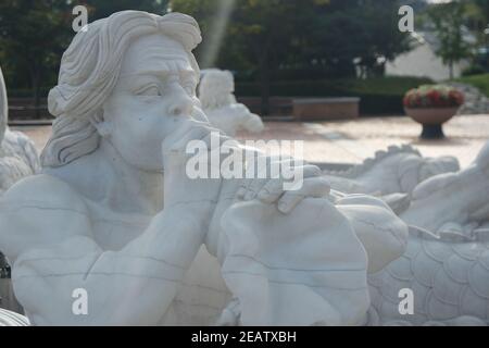 Steinskulptur eines Triton, der auf seine Muscheltrompete bläst. Stockfoto