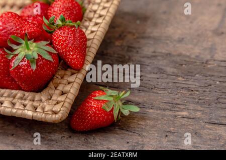 Frische saftige Erdbeeren im Korb. Weidenkorb voller frisch gepflückte Erdbeeren auf vintage Holz- Hintergrund. Zeit zum essen Erdbeeren. Stockfoto