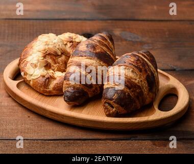 Zwei gebackene Croissants liegen auf einem Holztablett Stockfoto