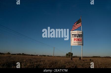 Smithville, Texas, USA. Februar 2021, 2nd. Ein Landwirt außerhalb von Smithville im Bastrop County, TX, fliegt drei Monate nach der Novemberwahl, wo das republikanische Ticket verloren hat, eine leicht zerfetzte amerikanische Flagge über einem Trump-Pence-Wahlkampfschild. Viele ländliche Texaner weigern sich immer noch, einen demokratischen Sieg zu akzeptieren. Quelle: Bob Daemmrich/ZUMA Wire/Alamy Live News Stockfoto