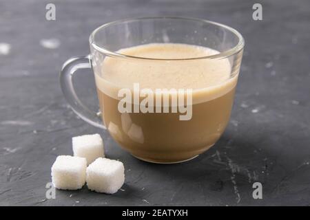 Eine Tasse Kaffee und Zuckerwürfel auf dunklem Hintergrund. Nahaufnahme Stockfoto