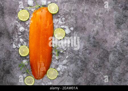 Frisches, rohes Lachsfischsteak mit Gewürzen auf Eis auf dunklem Steingrund. Kreatives Layout aus Fisch, Draufsicht, flache Lage mit Freiraum Stockfoto