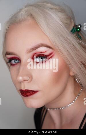 Junge blonde Frau mit rotem Glitzer Make-up Stockfoto