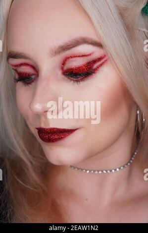 Junge blonde Frau mit rotem Glitzer Make-up Stockfoto