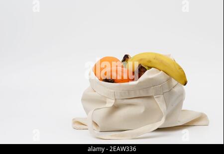 Beigefarbener Stoffbeutel mit frischen Früchten auf weißem Hintergrund, Platz für eine Inschrift Stockfoto