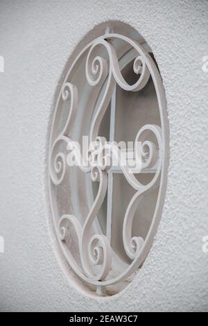 Rundes Fenster und Grill mit klassischem Design an weißer Wand. Fenster isoliert auf helle Farbe Wand. Hausdekorationen Stockfoto
