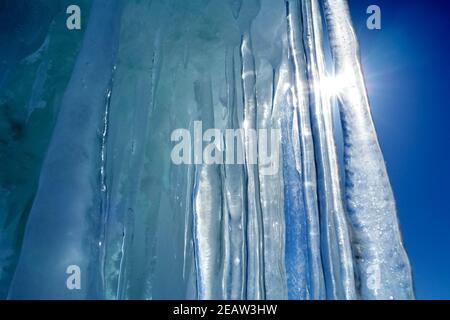 Lange Eiszapfen aus Eis gegen blauen Himmel und Sonne. Stockfoto