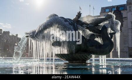 Gefrorene Brunnen Statuen von Trafalgar Square in London. Eiszapfen, die mystisch an einem bronzenen Brunnen hängen Stockfoto