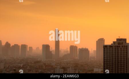 Luftverschmutzung in Bangkok, Thailand. Smog und Feinstaub von PM2,5 bedeckten Stadt am Morgen mit orangefarbenem Sonnenaufgangshimmel. Stadtbild mit verschmutzter Luft. Schmutzige Umgebung. Giftiger Staub in der Stadt. Ungesunde Luft. Stockfoto