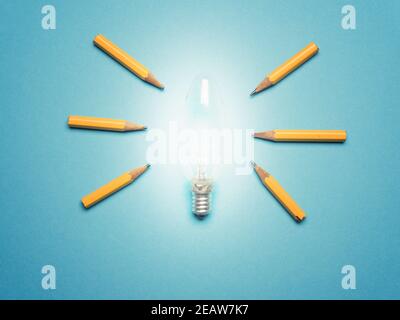 Eine glühende Glühbirne mit 6 Bleistiften als Lichtstrahlen, Neue Ideen oder Kreativitätskonzept auf blauem Hintergrund Stockfoto