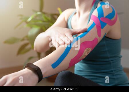 Junge fit Frauen zeigen auf ihrem Ellbogen angewendet elastische kinetische Band. Kinesiologie Physikalische Therapie. Stockfoto