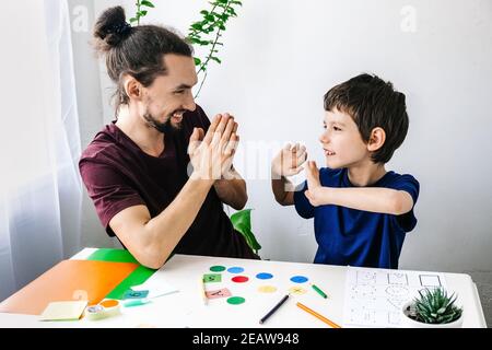 Glücklicher Autismus Junge während der Therapie mit Schulberater, Lernen und Spaß zusammen Stockfoto