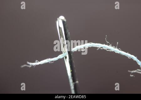 Kleine Nadel mit Faden in der Öse, isoliert über dem schwarzen Hintergrund. Stockfoto