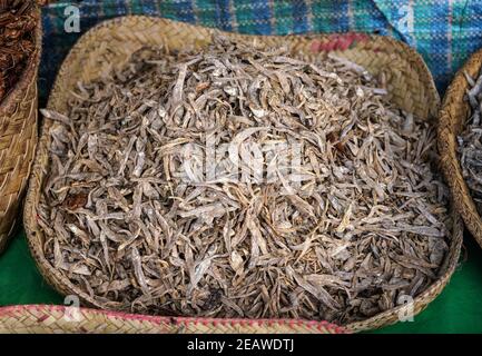 Kleine getrocknete Fische im Strohkorb auf dem Lebensmittelmarkt in Ranohira, Madagaskar, Nahaufnahme Detail Stockfoto