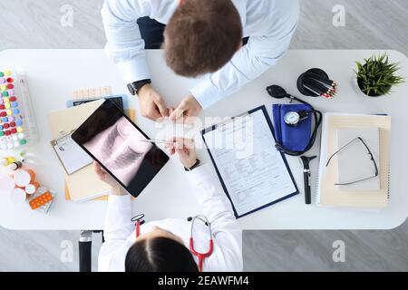 Arzt, der die Röntgenaufnahme des Patienten auf der Tablette zeigt Stockfoto