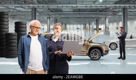 Reifer Mann und eine weibliche Auto Mechaniker Blick auf ein Laptop-Computer in einer Autowerkstatt Stockfoto