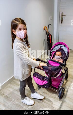 Mädchen mit Gesichtsmaske bereit für einen Spaziergang zu gehen Mit ihrer Puppe mit Maske Stockfoto