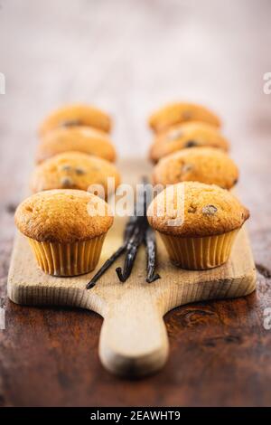 VanilleMuffins. Süße Cupcakes und Vanilleschoten auf Holztisch. Stockfoto