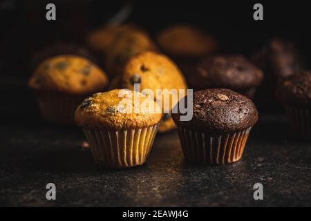 Muffins mit Schokolade und Vanille. Süße Cupcakes auf schwarzem Tisch. Stockfoto