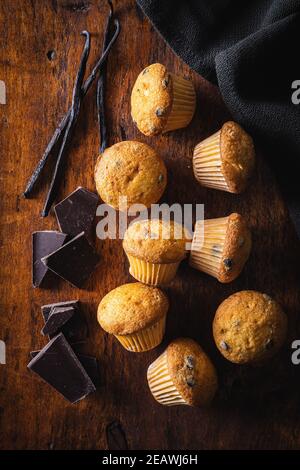 VanilleMuffins. Süße Cupcakes mit Schokolade und Vanilleschoten auf Holztisch. Draufsicht. Stockfoto