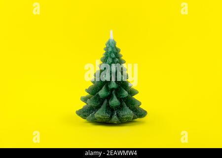 Grüner Weihnachtsbaum Kerze auf gelbem Hintergrund. Winterkarte. Feiertags- und Feiertagskonzept. Nachhaltige Weihnachten, keine Abfälle, umweltfreundlich Stockfoto