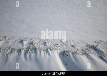 Ansicht von oben und aus der Nähe auf dicke Schneeschicht bedeckt Grasboden. Stockfoto