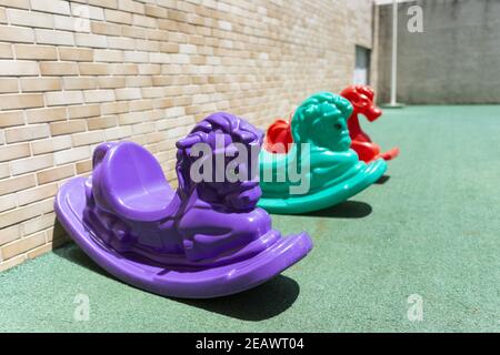 Bunte Kunststoff-Schaukelstühle im Spielplatz Stockfoto