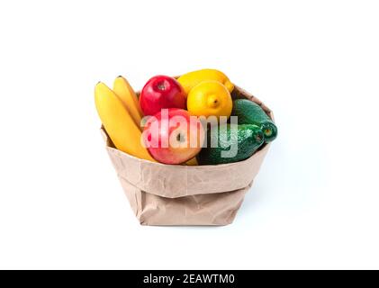 Die Basteltasche ist gefüllt mit Früchten: Bananen, Avocados, Zitronen und Äpfeln auf weißem Hintergrund. Stockfoto
