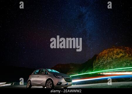 Lange Exposition des Autos vor der Milchstraße mit leichten Spuren von Taxi fahren hinter auf einem Hügel auf La Gomera, Kanarienvogel, Stargazing ohne Lichtverschmutzung Stockfoto