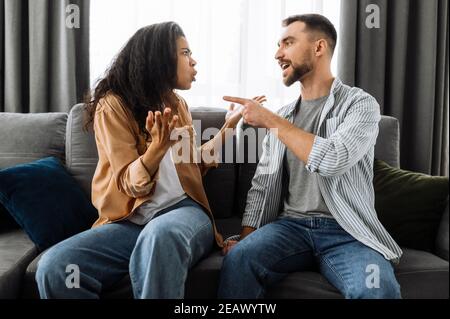 Verheiratete junge Paar emotionale diskutieren über etwas, sie haben Problem. afroamerikanische Frau und kaukasischen Mann sind nicht miteinander einverstanden haben ein Stockfoto