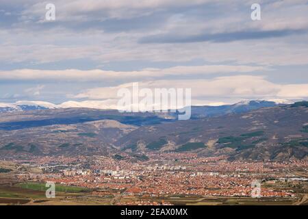 Blick auf Pirot Stadt von einem Aussichtspunkt mit entfernten, schneebedeckten Berggipfeln im Hintergrund und bewölktem Himmel oben Stockfoto