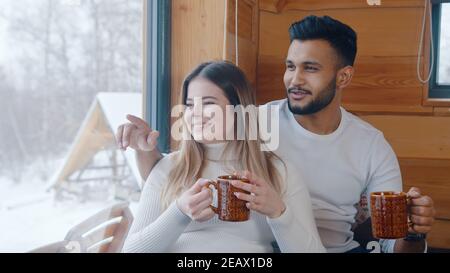 Glückliches junges Paar verbringen Valentinstag verschneiten Tag in gemütlichen Haus, trinken heiße Schokolade am Fenster. Hochwertige Fotos Stockfoto