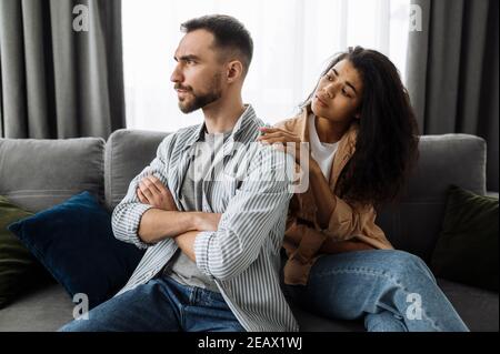 Ein Ehepaar findet die Beziehung heraus, ein Streit zwischen Liebenden. Multirassisches Paar in der Liebe streitsüchtig zu Hause auf der Couch über Haushalt oder Finanzierung Stockfoto
