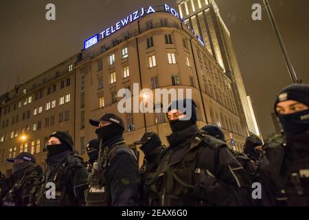 Polizeibeamte stehen während des Protestes auf dem Gebäude des Polnischen Informationsfernsehens (TVP INFO) auf Wache. Mehrere private TV- und Radiostationen und Webportale in Polen haben sich am Mittwoch aus Protest gegen eine vorgeschlagene Medienwerbesteuer, die die Unabhängigkeit und die Vielfalt der Ansichten der Branche bedroht, aus der Luft gedrängt. Anstelle ihrer üblichen Shows liefen die Outlets schriftliche oder gesprochene Slogans wie „das war dein Lieblingsprogramm“ und „Medien ohne Wahl“. Am Abend versammelten sich Menschen vor dem TVP INFO (Polnisches Informationsfernsehen) Hauptquartier, um gegen die Proteste zu protestieren Stockfoto