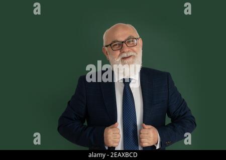 Selbstbewusster männlicher Lehrer oder Professor mittleren Alters, der vor einem leeren Kreidetafel steht. Lustiger Professor oder Wissenschaftler in einem eleganten schwarzen Anzug Stockfoto