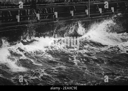 Graustufen Aufnahme von Wellen krachenden Brücke Wand Stockfoto