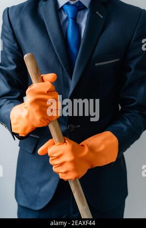 Geschäftsmann in einem monochromatischen blauen Anzug hält Reinigungsmittel für das Haus, Home Office Stockfoto