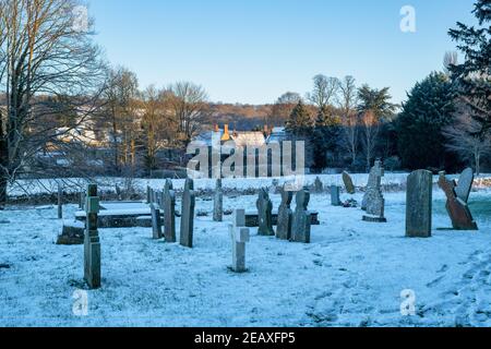 Grabsteine in St. Peter und St. Paul Kirchhof im Schnee. Long Compton, Warwickshire, England Stockfoto