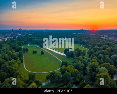 Wundervolle Gesamtansicht über den Englischen Garten von München früh bei einem sommerlichen Sonnenaufgang. Der grüne öffentliche Sightseeing-Hotspot wurde von oben gefilmt. Stockfoto