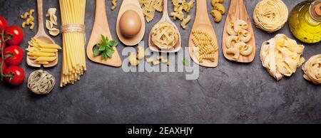 Verschiedene Nudeln in Löffeln, Tomaten und Olivenöl. Draufsicht flach liegend Stockfoto