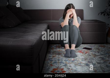 Junge Frau, die an Depressionen leidet. Müde Frau, die auf dem Boden sitzt. Psychische Gesundheit, geistige Burnout Konzept. Stockfoto