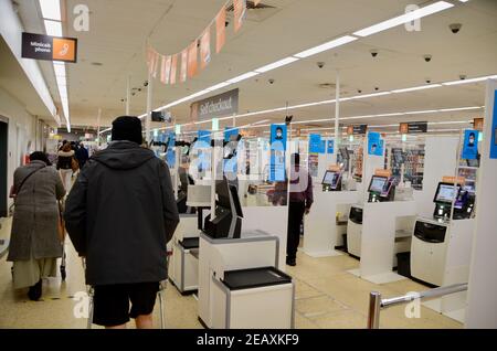 Sozial entfernter Self Checkout Bereich in Sainsbury's haringey london mit Einkäufer und Mitarbeiter Stockfoto