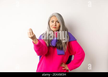 Lustige asiatische Frau starrte wütend und verwirrt, schüttelnde Finger, mürrisch vor weißem Hintergrund stehend Stockfoto