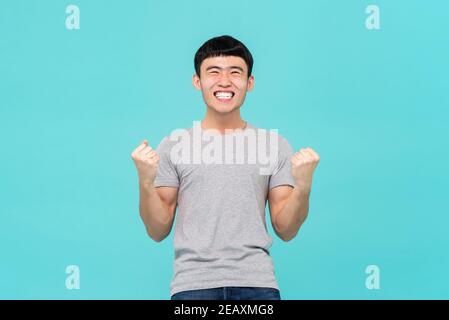Glücklich, aufgeregt junger asiatischer Mann hob seine Fäuste tun ja Geste Erfolge feiern Stockfoto
