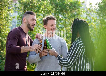 Gay Paar und afroamerikanische Frau Freund genießen Alkohol trinken Und draußen im Garten reden Stockfoto