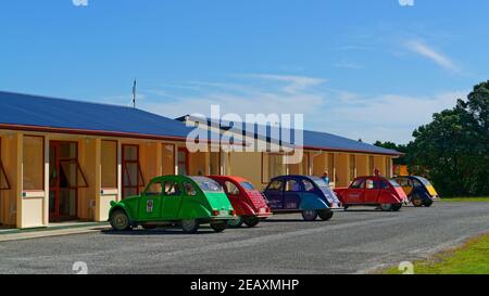 Eine Gruppe von Citroen 2CV Oldtimer in verschiedenen Farben, geparkt vor einem Motel, Westport, Neuseeland. Stockfoto