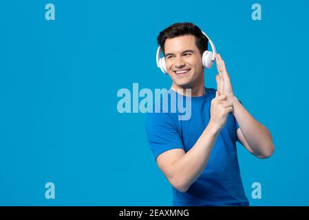 Ein amerikanischer Mann mit einem netten Lächeln, der Kopfhörer trägt und dem man gerne zuhören kann Seine Lieblingssongs isoliert auf blauem Studiohintergrund mit Kopie Platz Stockfoto