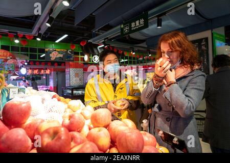 Wuhan, Chinas Provinz Hubei. Februar 2021, 2nd. Peng Zilong (L), ein 30-jähriger Deliveryman, kauft mit der italienischen Professorin Sara Platto beim Frühlingsfest in Wuhan, der zentralchinesischen Provinz Hubei, am 2. Februar 2021 ein. Quelle: Xiong Qi/Xinhua/Alamy Live News Stockfoto