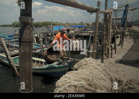 Ein Arbeiter, der auf dem Boot nach dem Waschen von Rattankörben am Landungsstrand von Kamal Muara, einem Fischerdorf, das auch als grünes Muschelproduktionszentrum im Küstengebiet von Jakarta, Indonesien, bekannt ist, läuft. Stockfoto