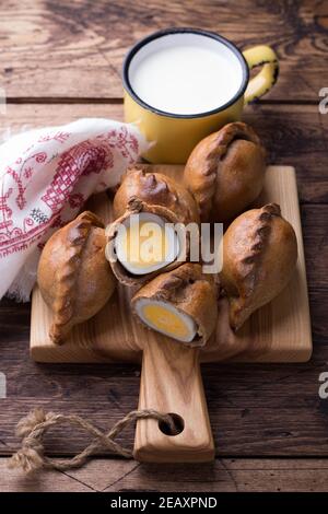 Russische traditionelle Roggenpasteten mit Ei, kokurki, auf einem Holztisch, rustikalen Stil. Köstliche hausgemachte Urlaubskost und Snack Stockfoto